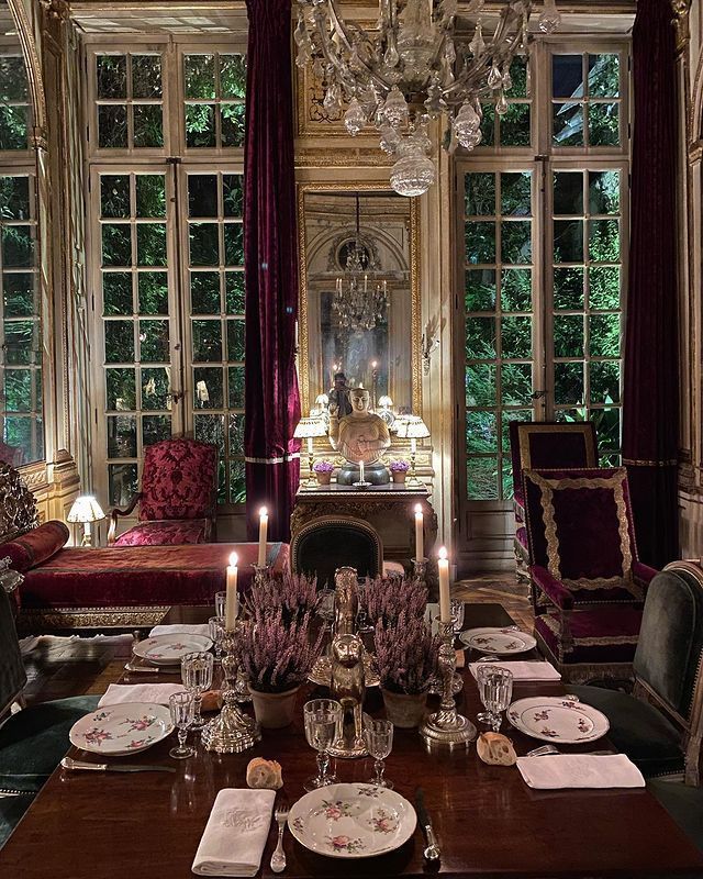 a fancy dining room with chandelier, table and chairs in front of large windows