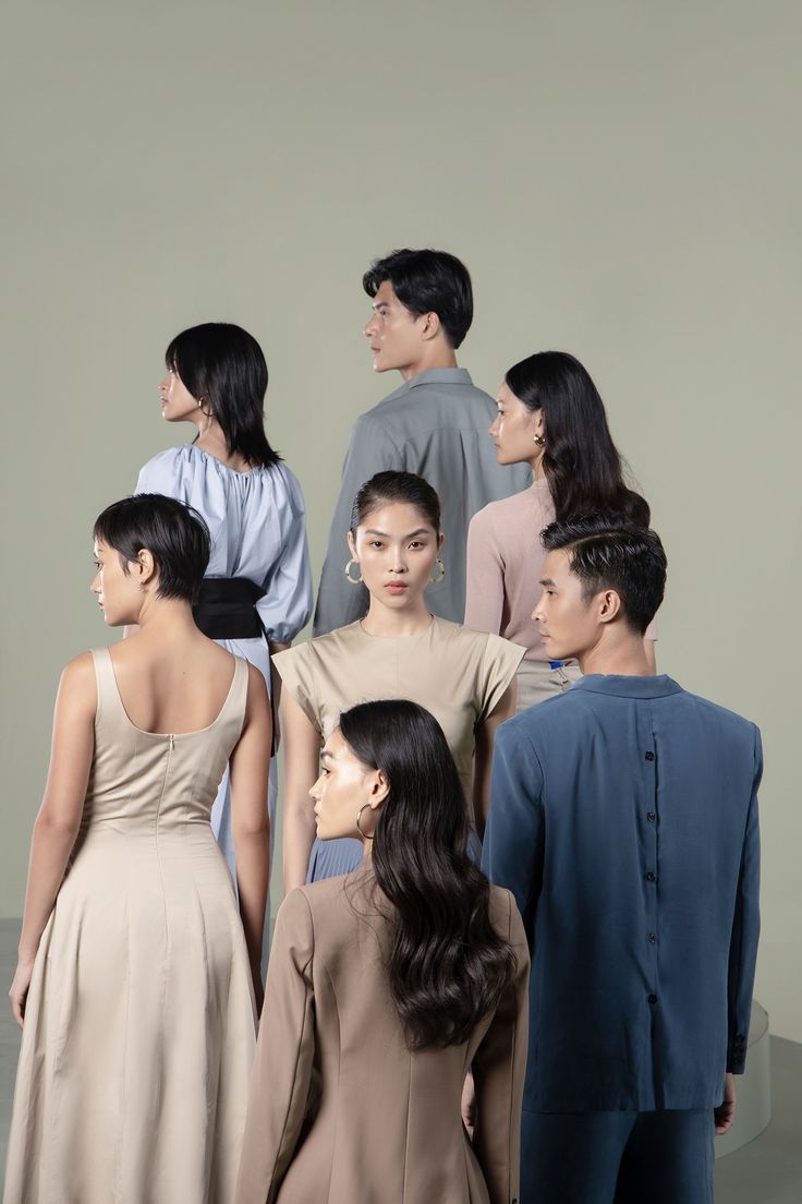 a group of people standing next to each other in front of a white wall with one woman looking at another man