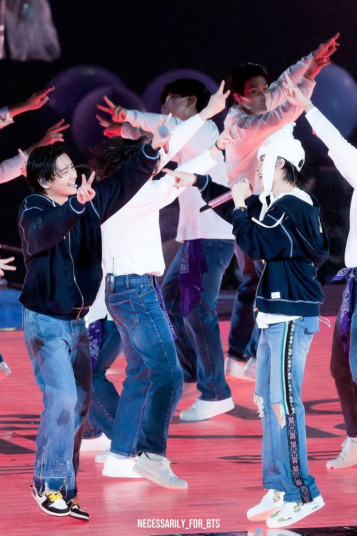 group of young people dancing on stage with their hands in the air