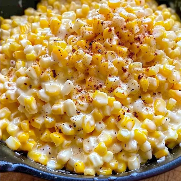 a bowl filled with corn on top of a wooden table