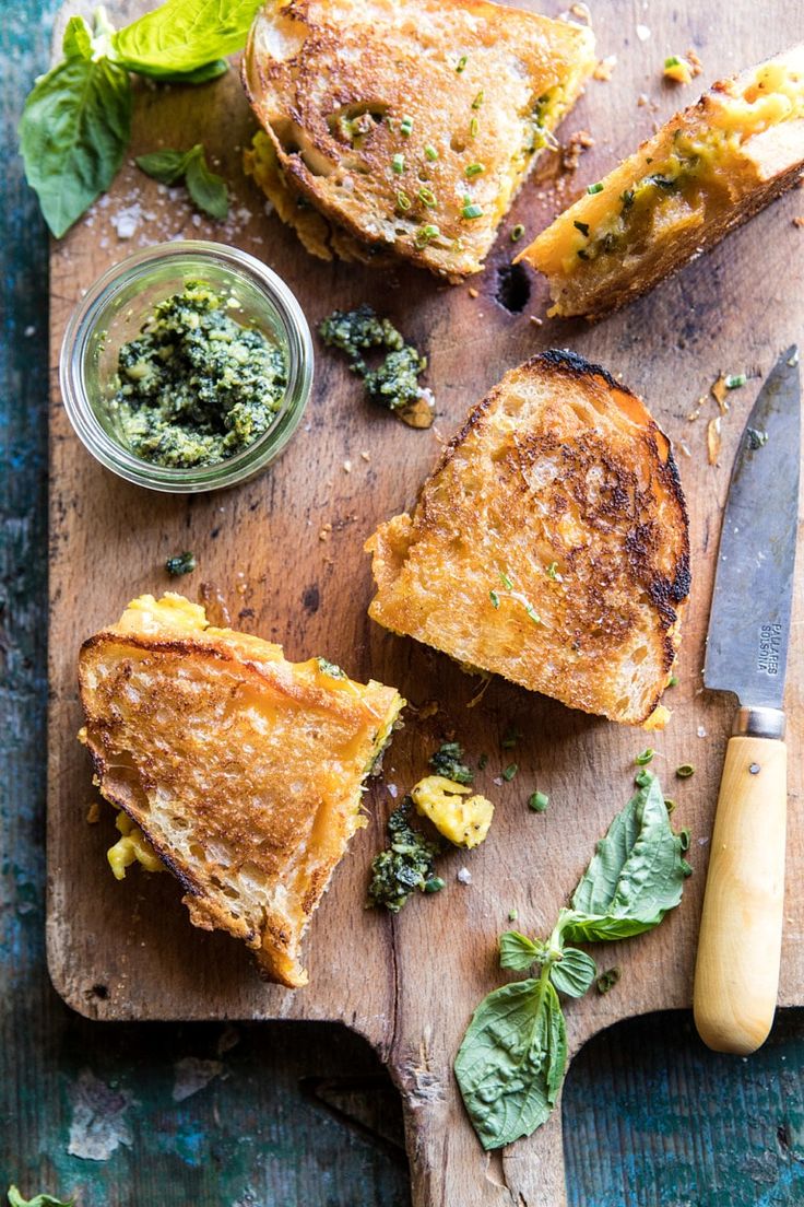 grilled cheese sandwiches with pesto sauce on a cutting board