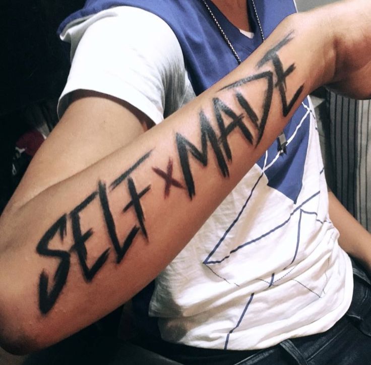 a man with a tattoo on his arm that says self made in black ink, sitting down