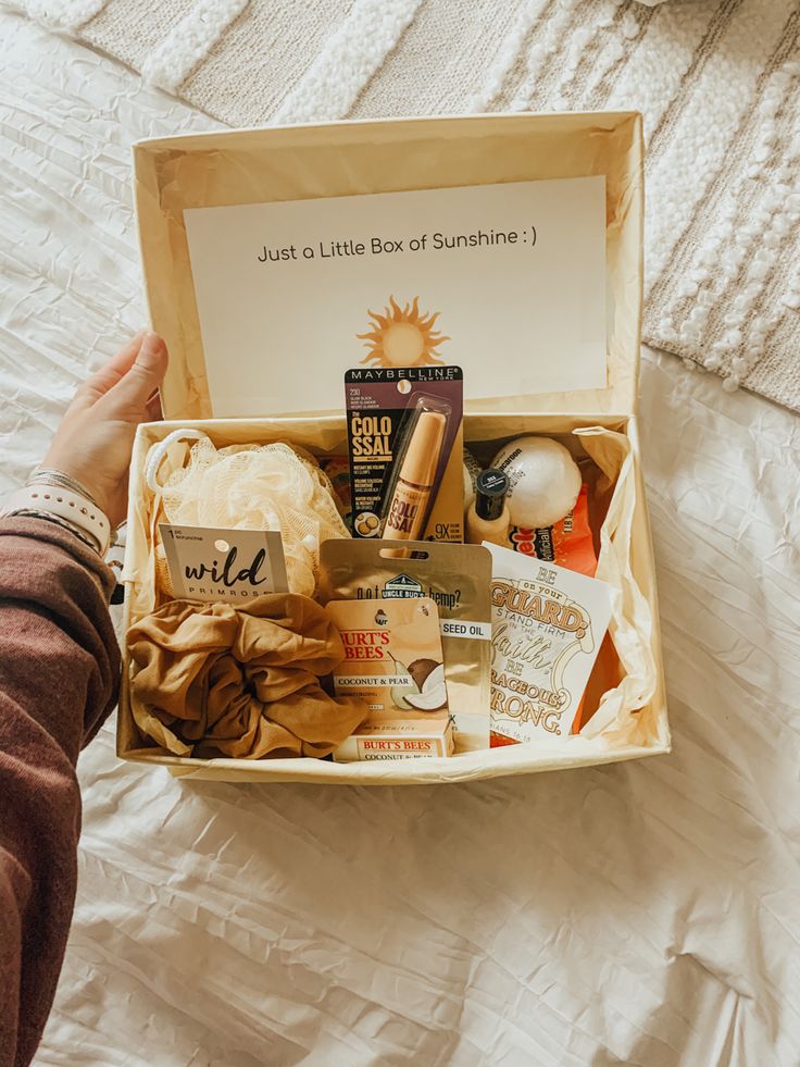 someone is holding an open box with various items in it on top of a bed