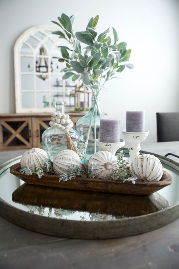 a tray with candles and flowers in it on a dining room table next to a vase