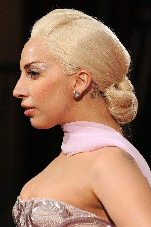 a woman with blonde hair wearing a pink dress and tattoos on her neck is looking off to the side