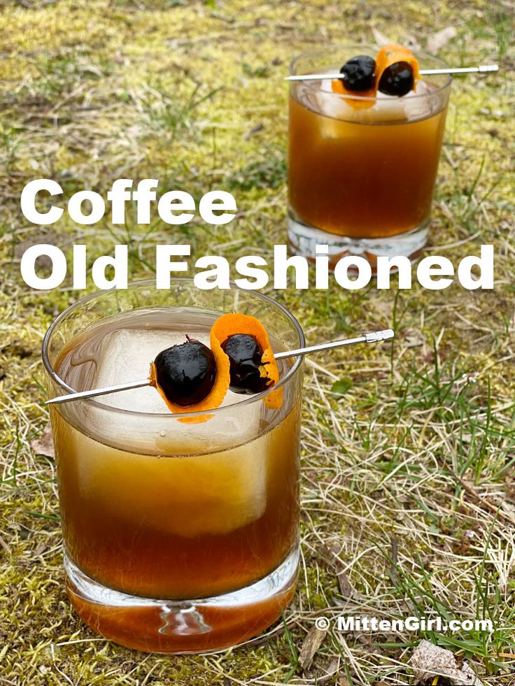 two glasses filled with coffee and orange peels on top of the drinks in them