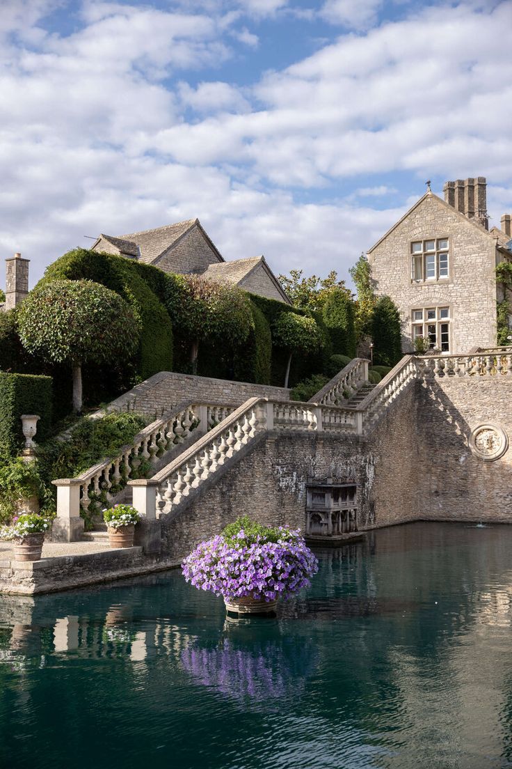 a large house with stairs and flowers in the water next to some steps that lead up to it