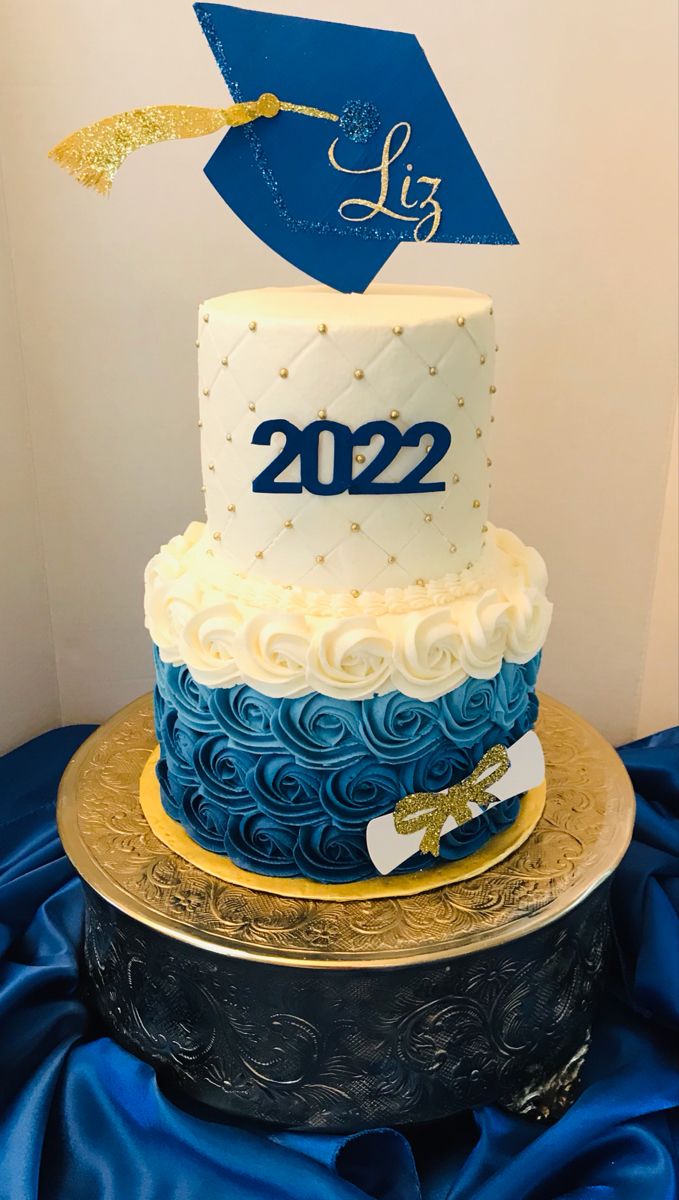 a blue and white graduation cake sitting on top of a gold plated platter