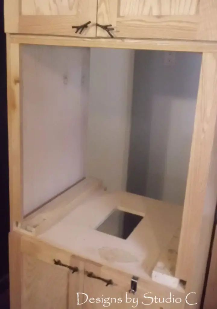 an unfinished kitchen cabinet with the door open