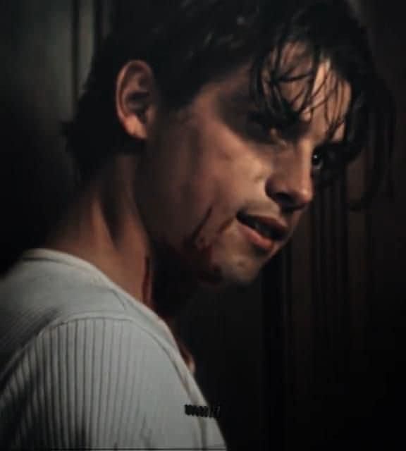 a man with blood all over his face and mouth in a dark room, looking at the camera