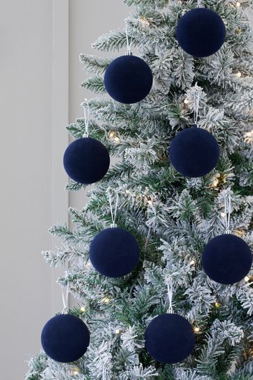 a christmas tree with blue ornaments hanging from it's branches and lights on the top