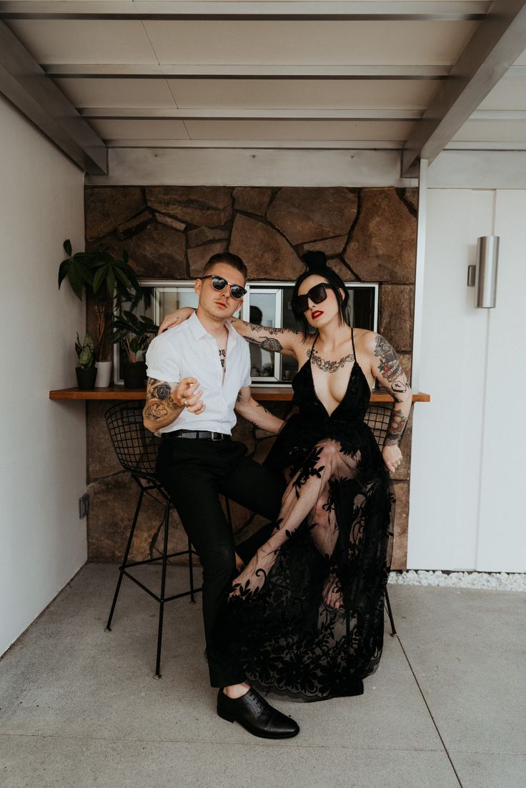 a man and woman sitting next to each other in front of a table with chairs