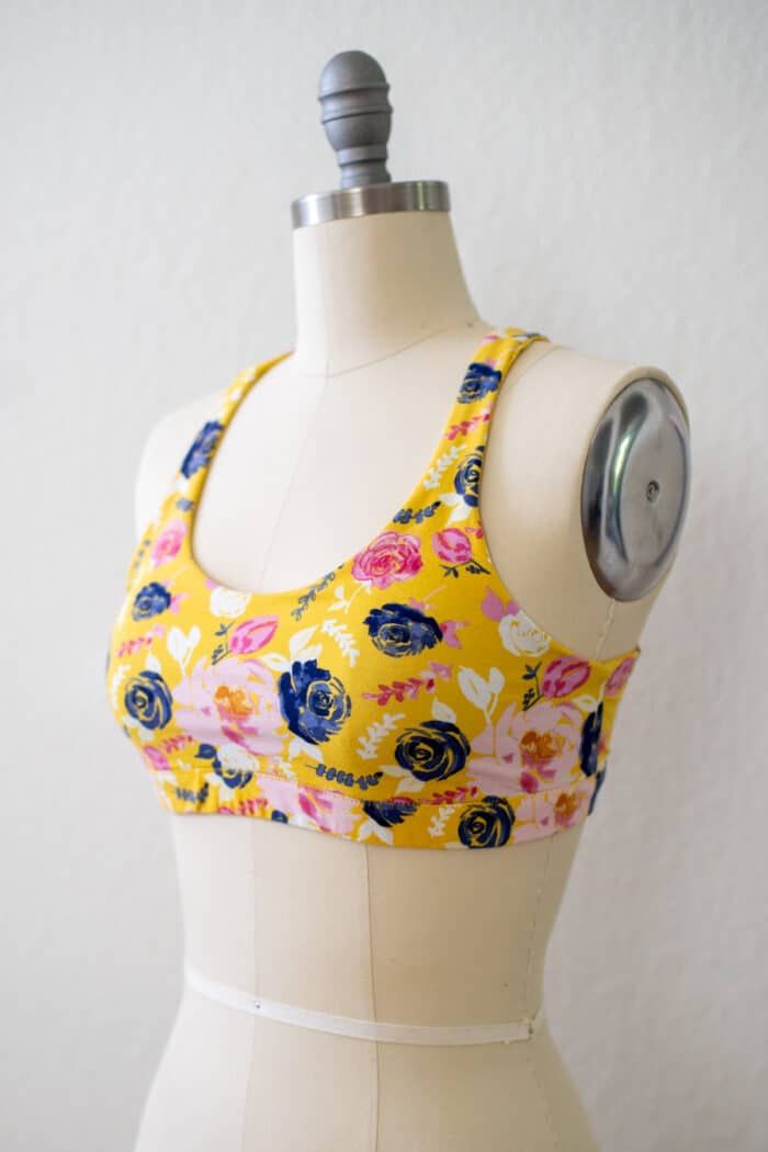 a female mannequin wearing a yellow and blue floral sports bra top with white trim