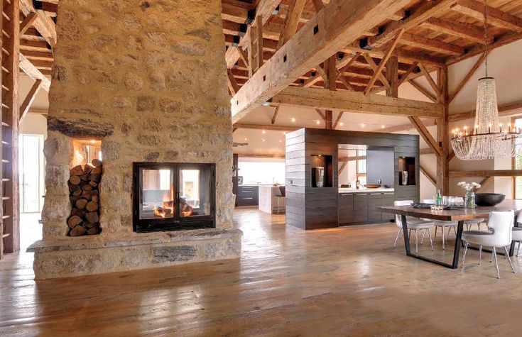 a living room filled with furniture and a fire place in the middle of a wooden floor