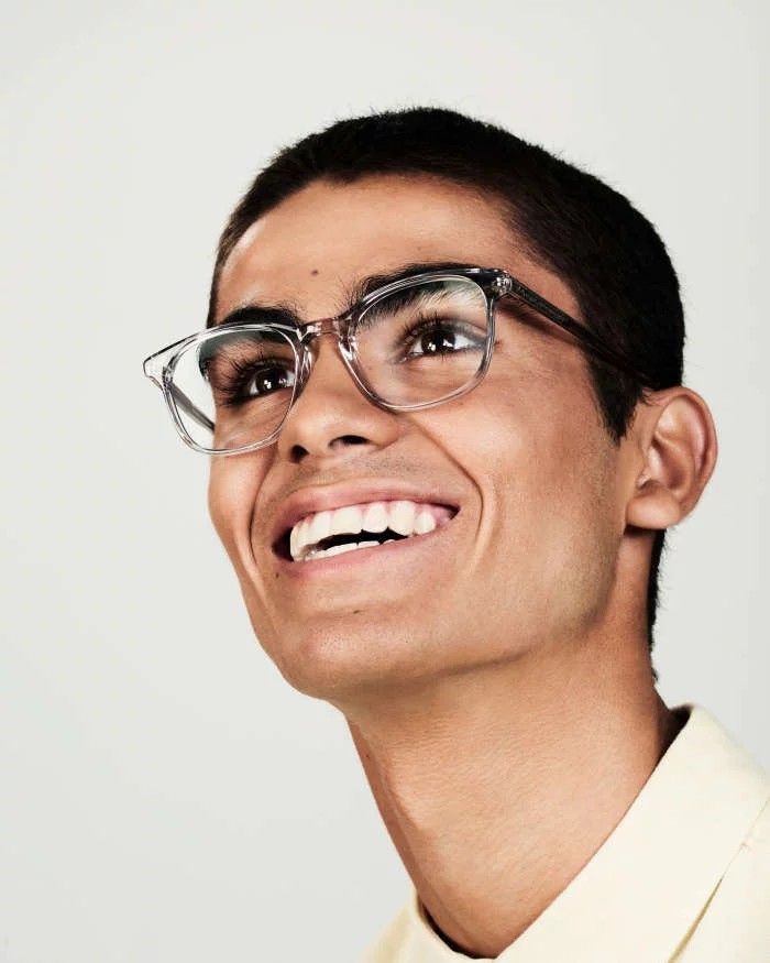 a man wearing glasses and smiling for the camera