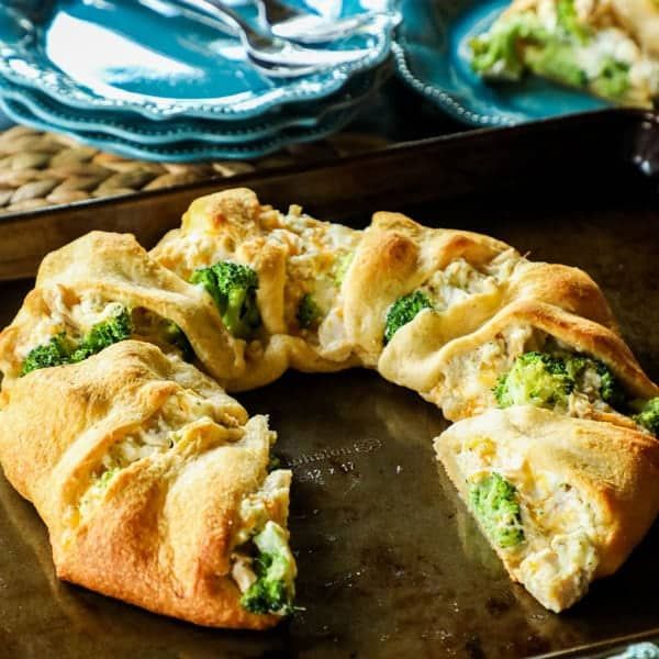 broccoli and cheese crescent pastry on a baking sheet with plates in the background