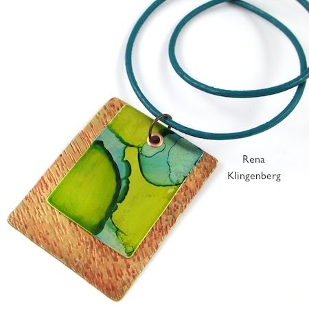 a green and brown square shaped pendant on a blue cord