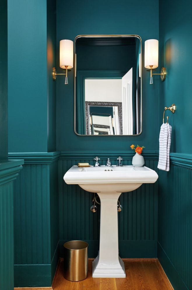 a white sink sitting under a bathroom mirror next to a wooden floor and green walls