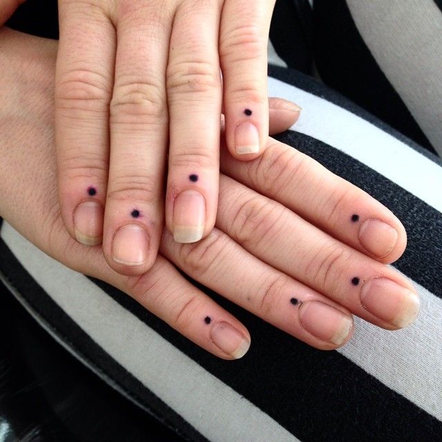 two hands holding each other with small black dots on their fingers and the middle finger