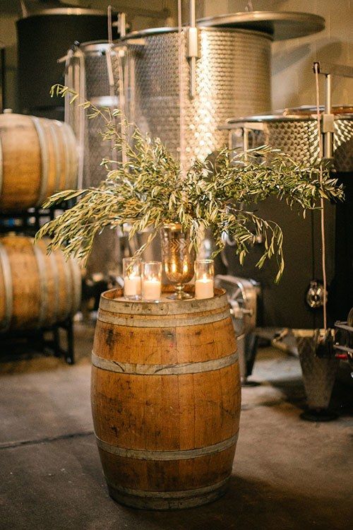 a wooden barrel with candles and greenery in it sitting next to some kegs