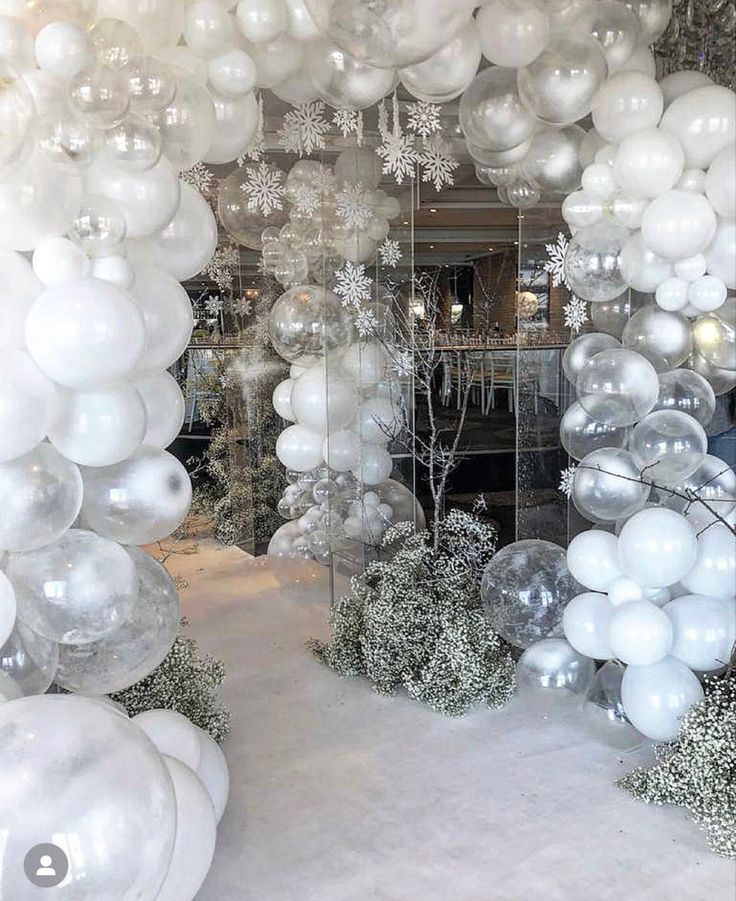 white balloons and snowflakes are hanging from the ceiling