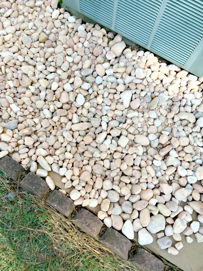 there is a pile of rocks on the ground next to an air conditioner outside