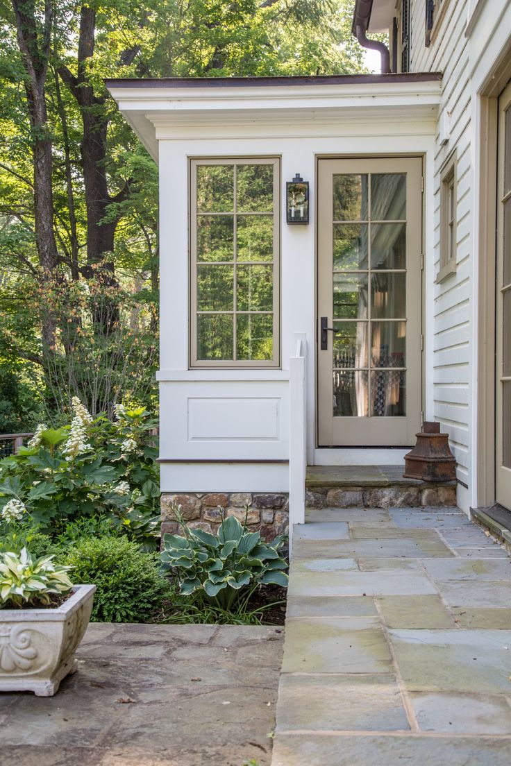 the front door of a white house with stone walkway