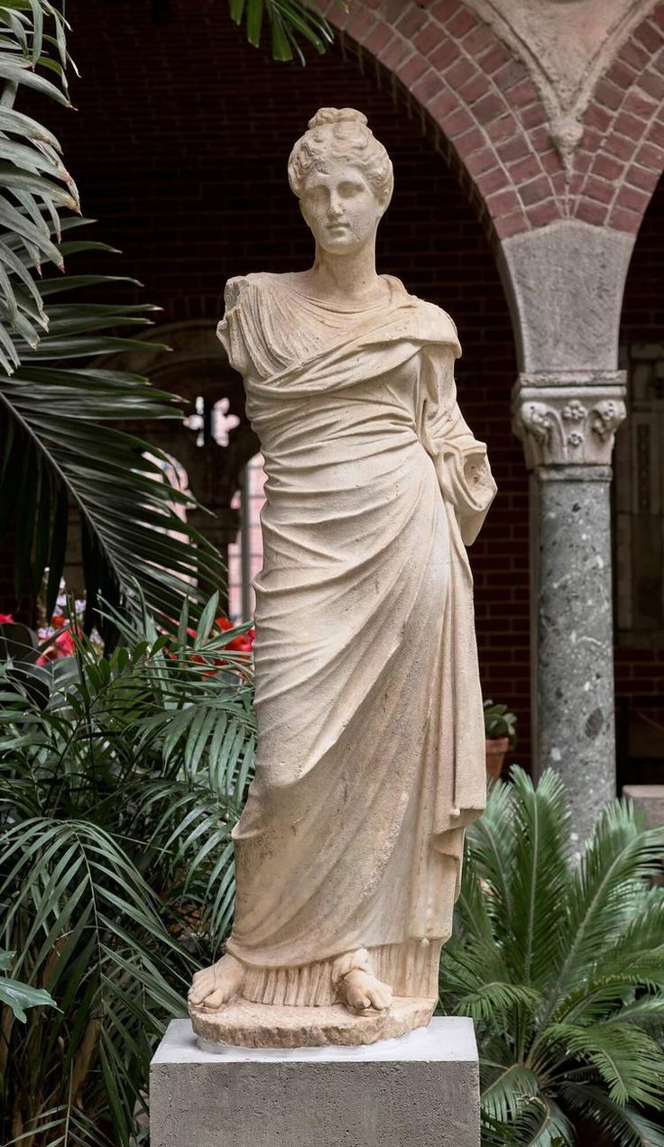 a statue of a woman standing in front of some plants