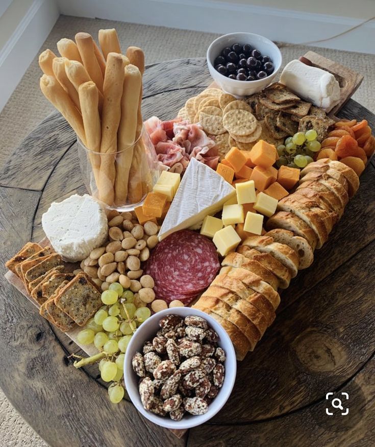 an assortment of cheeses, crackers, and meats on a wooden table