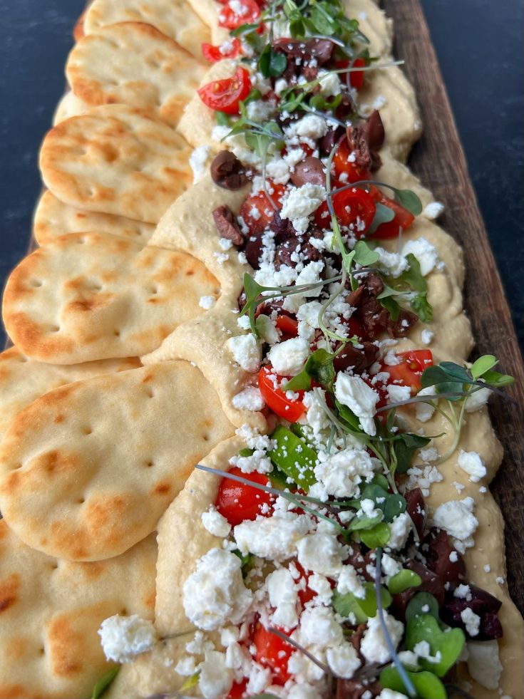 a long platter filled with lots of food on top of a wooden table next to crackers