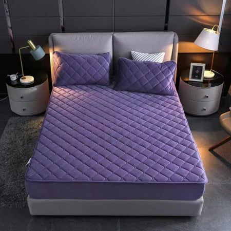 a bed with purple sheets and pillows in a room next to a night stand lamp