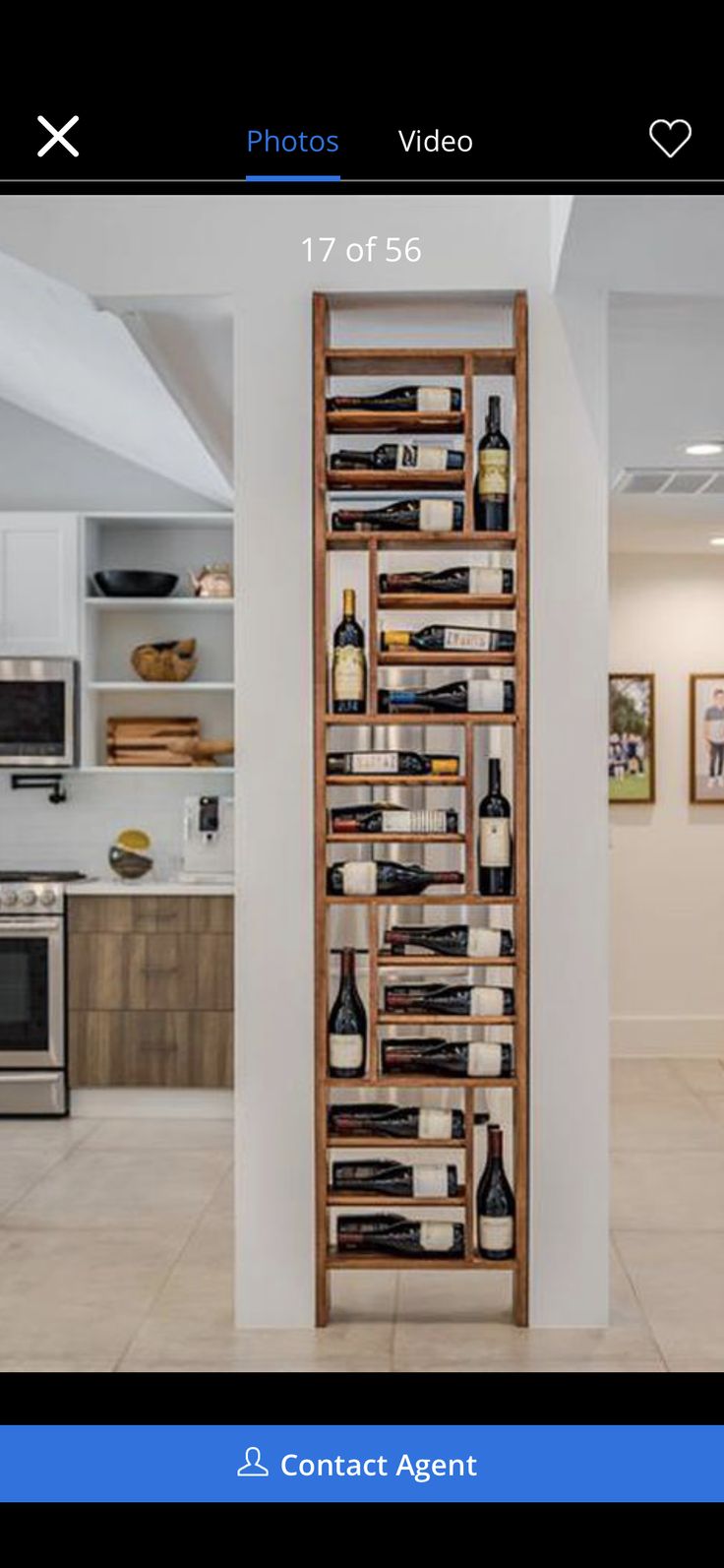 a large wooden shelf filled with lots of bottles and wine glasses on top of a tiled floor