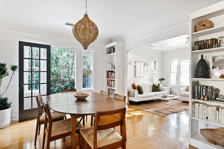 a dining room table and chairs in front of a bookshelf with open doors