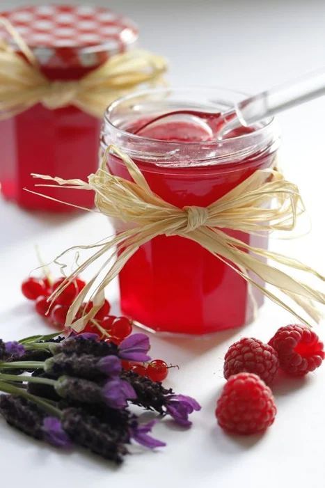 raspberry jam in a jar with fresh berries and lavenders on the side