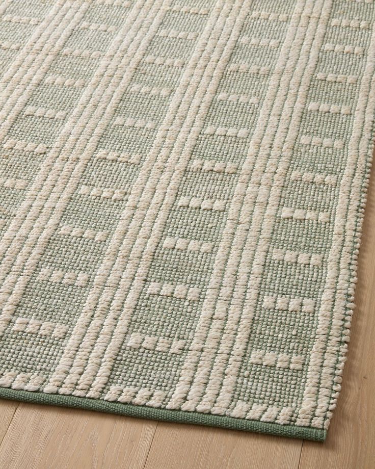 a green and white rug on top of a wooden floor next to a wood floor