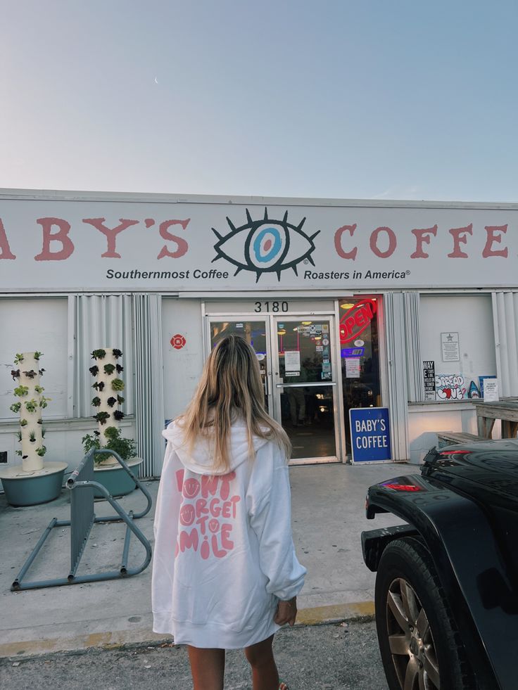 a woman standing in front of a coffee shop with an eye on it's sign