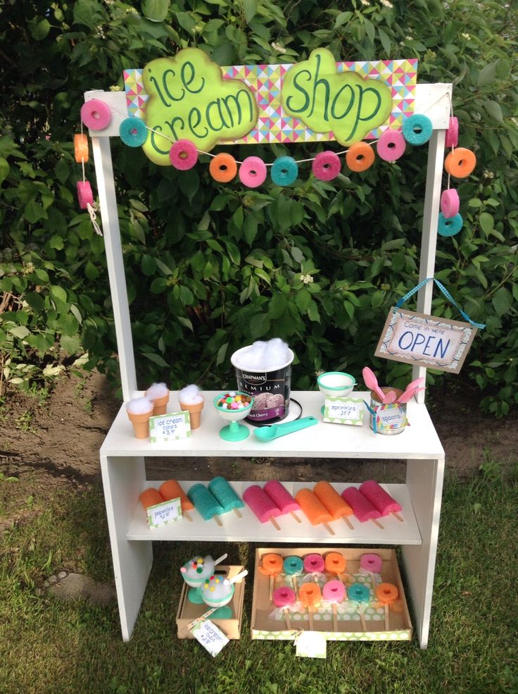 an ice cream shop stand with doughnuts and cupcakes on the table