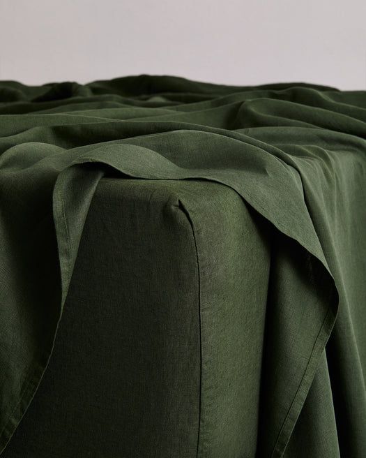 a close up view of the fabric on a bed with dark green sheets and pillows