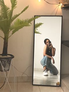 a woman sitting on the floor in front of a mirror talking on her cell phone