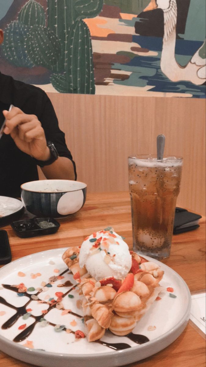 a person sitting at a table with food and drinks