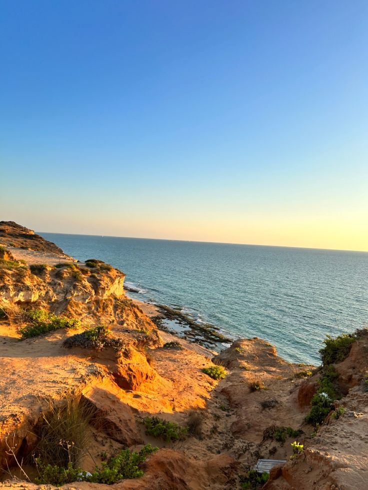 a bench sitting on the edge of a cliff overlooking the ocean