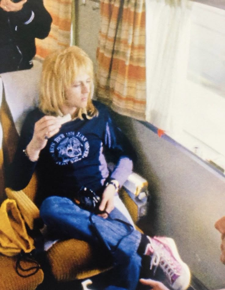 a woman sitting on top of a train seat next to another person holding a cell phone