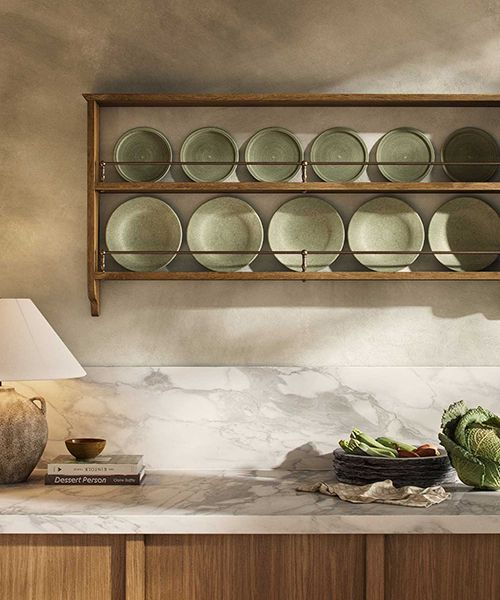 a kitchen counter with plates and bowls on it, along with a lamp in the corner