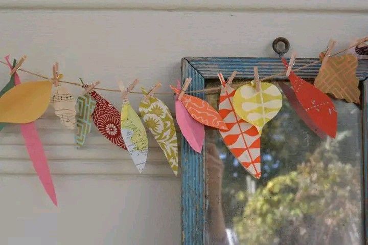 colorful paper hearts are hanging from a clothes line on a window sill in front of a mirror