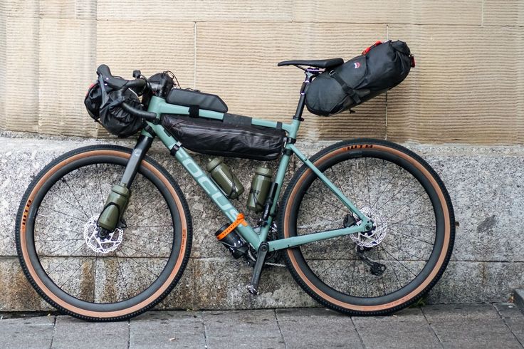 a bicycle parked next to a wall with a backpack on it's back end