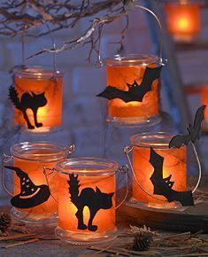 halloween candles with bats and pumpkins in mason jars on a table outside at night