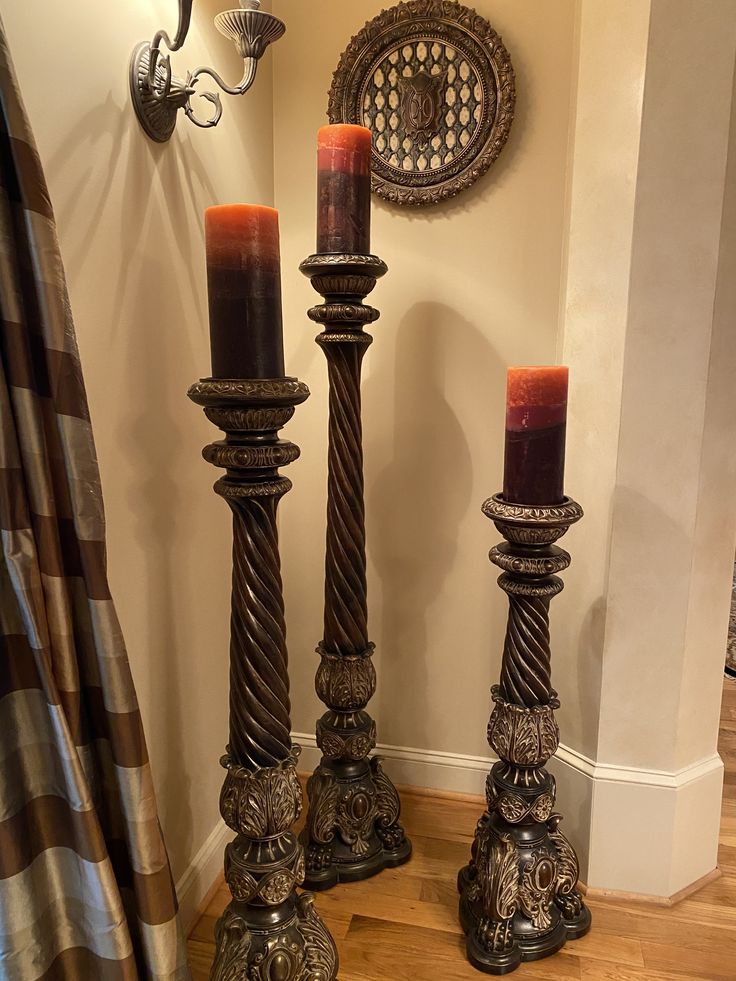 two tall candles sitting next to each other on top of a wooden floor