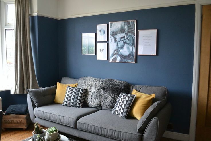 a living room with blue walls and pictures on the wall above the gray couches