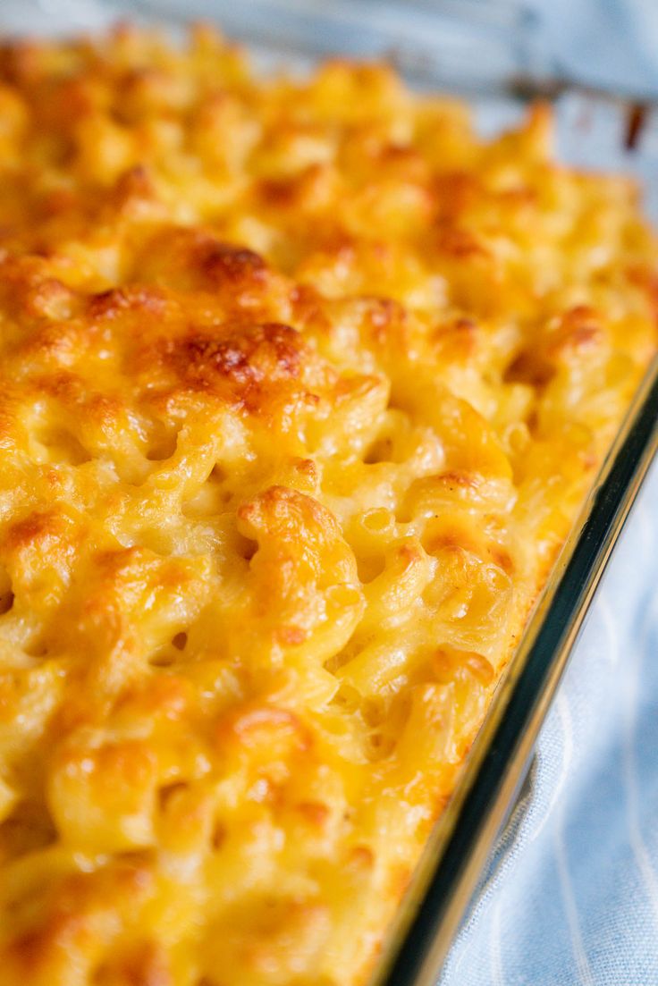 a cheesy casserole dish is sitting on a blue cloth covered table