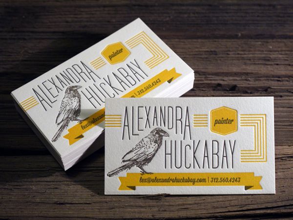 two business cards sitting on top of a wooden table with yellow and white lettering that reads alexandria huckaby